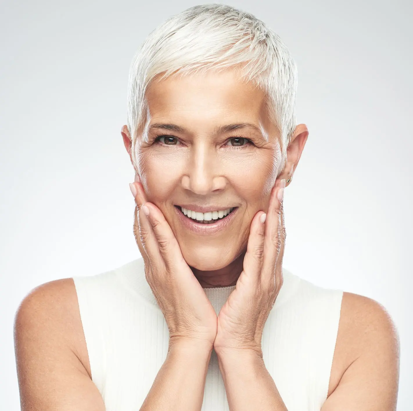 Senior woman posing in front of gray background. Otoplasty in Charleston County, SC