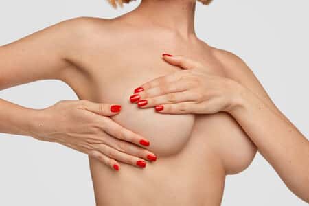 Photo of unrecognizable woman keeps hands on breast treats cancer in mammologist has hormonal changes during lactation period shows soft skin isolated over white wall Health care concept - Sweetgrass Plastic Surgery Health care concept